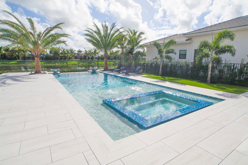 Large modern backyard rectangular infinity pool in Miami with a hot tub.