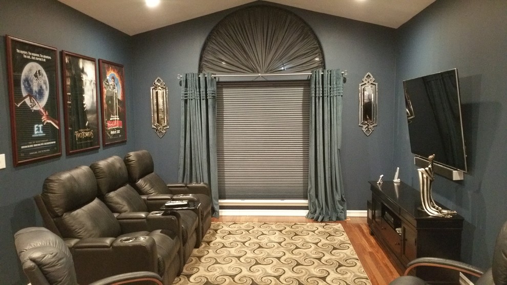 This is an example of a small transitional enclosed home theatre in New York with blue walls, medium hardwood floors and a wall-mounted tv.