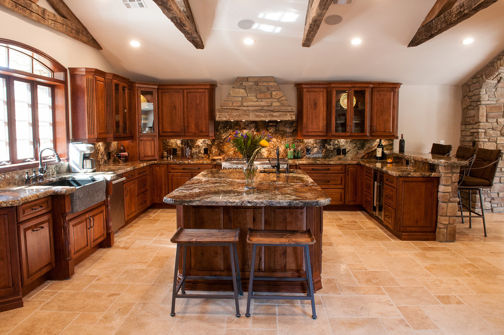 Photo of an expansive country u-shaped eat-in kitchen in Other with a farmhouse sink, stone slab splashback, with island, raised-panel cabinets, brown splashback, stainless steel appliances, beige floor, dark wood cabinets, granite benchtops, travertine floors and beige benchtop.
