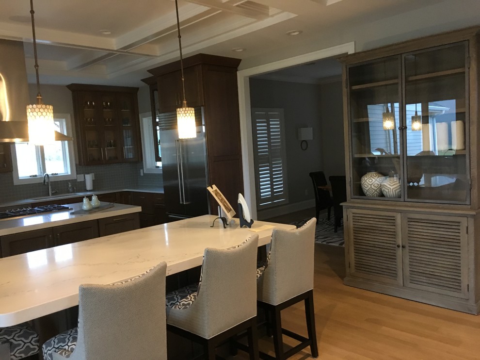 Open concept kitchen - mid-sized transitional light wood floor and beige floor open concept kitchen idea with an undermount sink, recessed-panel cabinets, dark wood cabinets, quartz countertops, gray backsplash, porcelain backsplash, stainless steel appliances and two islands