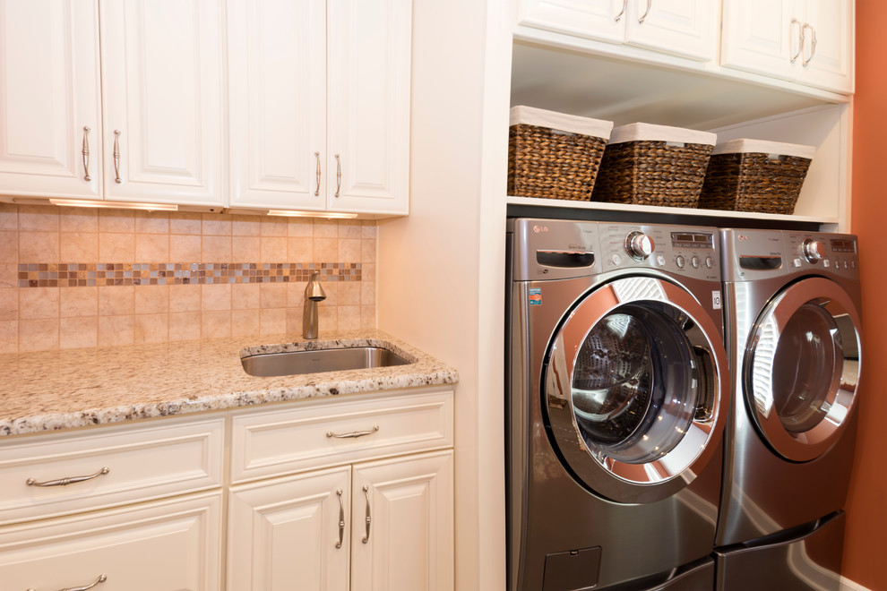 This is an example of a traditional laundry room in New York with white cabinets and a side-by-side washer and dryer.