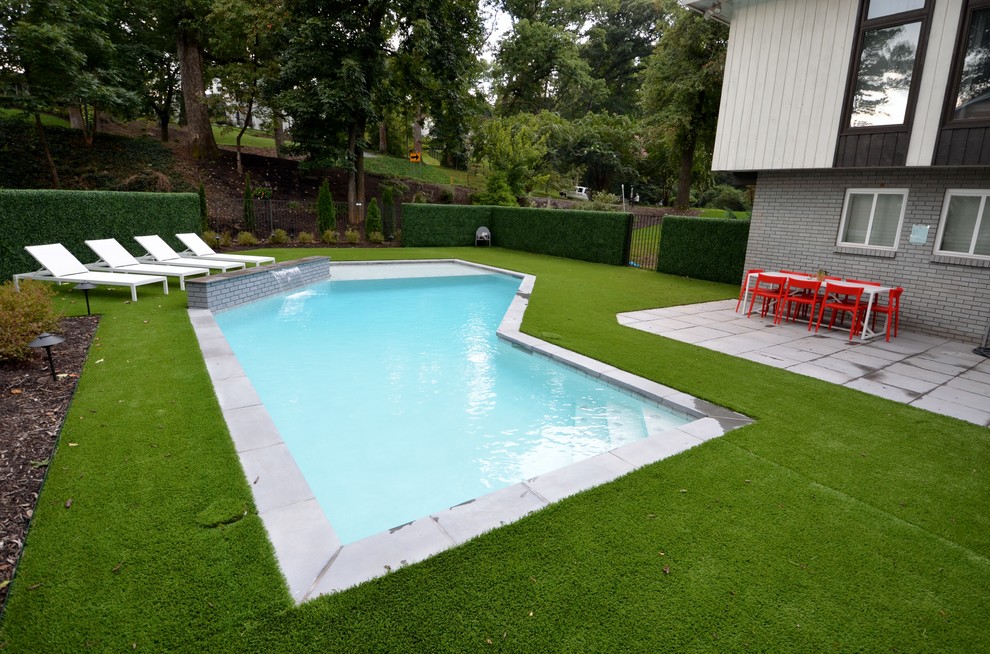 This is an example of a mid-sized modern backyard custom-shaped lap pool in Other with a water feature and concrete pavers.