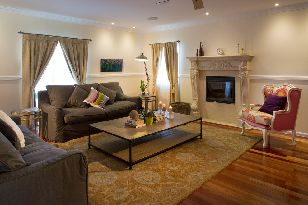Photo of a large traditional open concept living room in Brisbane with a library, beige walls, medium hardwood floors, a standard fireplace, a stone fireplace surround and a built-in media wall.