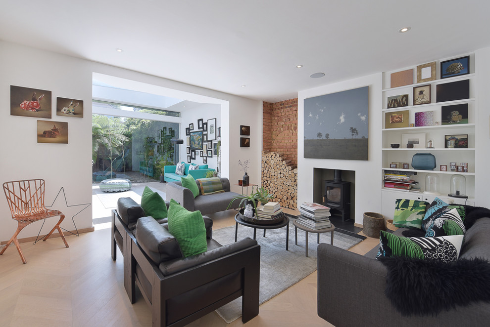 This is an example of a mid-sized contemporary enclosed living room in London with white walls, light hardwood floors, a wood stove, a plaster fireplace surround and beige floor.