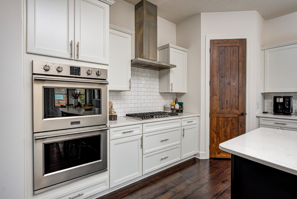 Inspiration for a mid-sized contemporary galley eat-in kitchen in Indianapolis with an undermount sink, shaker cabinets, white cabinets, quartz benchtops, white splashback, subway tile splashback, stainless steel appliances, medium hardwood floors, with island and white benchtop.