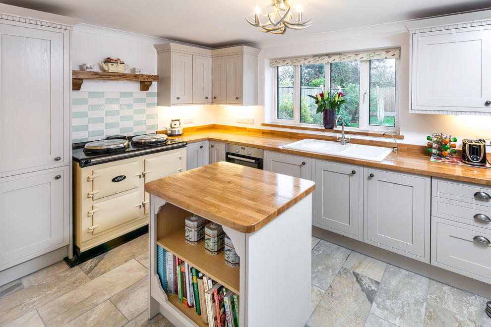 Country l-shaped kitchen in Essex with a drop-in sink, recessed-panel cabinets, grey cabinets, wood benchtops, multi-coloured splashback, coloured appliances, with island and grey floor.