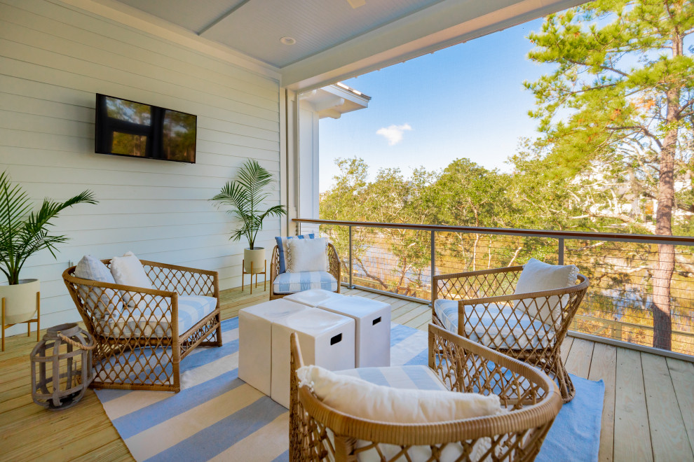 Aménagement d'une très grande terrasse au premier étage bord de mer avec une extension de toiture et un garde-corps en câble.