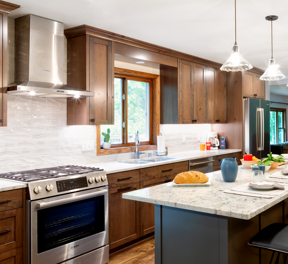 Inspiration for a mid-sized traditional galley eat-in kitchen in Minneapolis with a double-bowl sink, shaker cabinets, medium wood cabinets, granite benchtops, white splashback, ceramic splashback, stainless steel appliances, vinyl floors, with island and white benchtop.