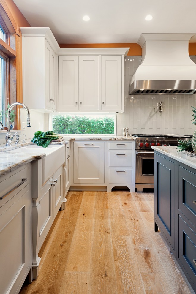 Inspiration for a mid-sized transitional u-shaped light wood floor and beige floor open concept kitchen remodel with an undermount sink, recessed-panel cabinets, gray cabinets, granite countertops, white backsplash, glass tile backsplash, stainless steel appliances and an island