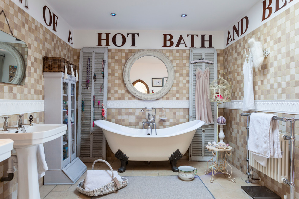 Inspiration for a traditional bathroom in London with a pedestal sink, a claw-foot tub, beige tile and white walls.