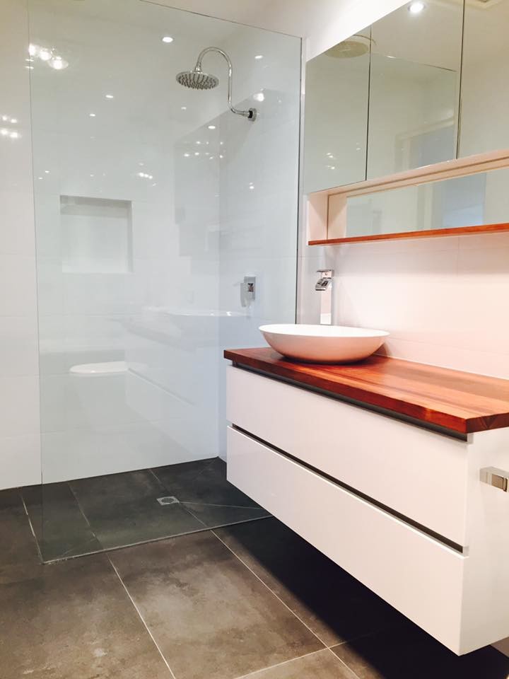 Photo of a mid-sized contemporary master bathroom in Melbourne with white cabinets, a corner tub, an open shower, a one-piece toilet, gray tile, porcelain tile, white walls, cement tiles, a vessel sink and wood benchtops.