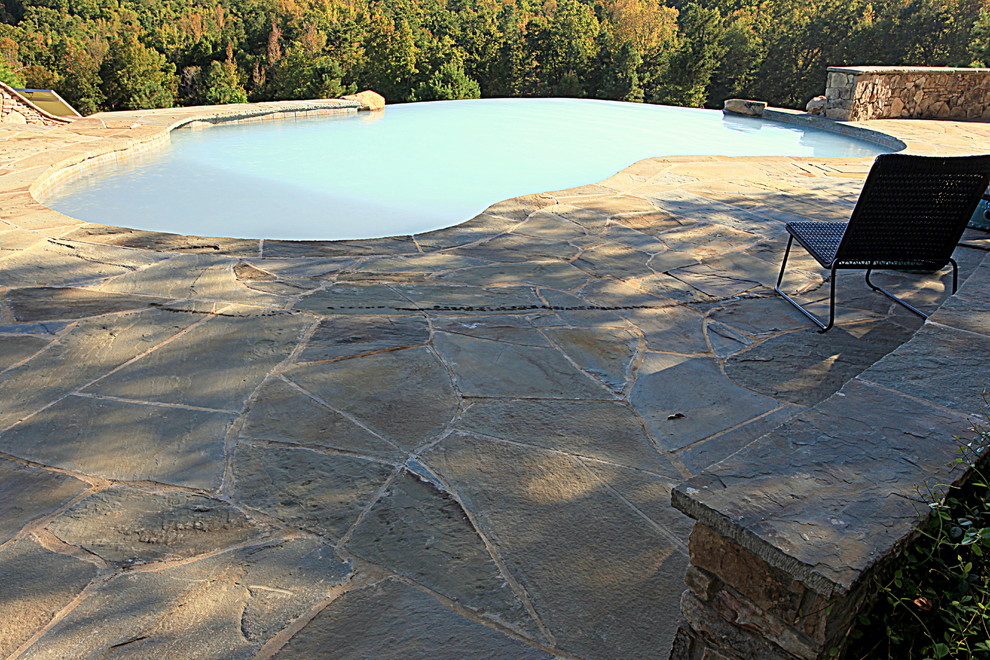 Inspiration for a large rustic backyard stone and custom-shaped infinity pool remodel