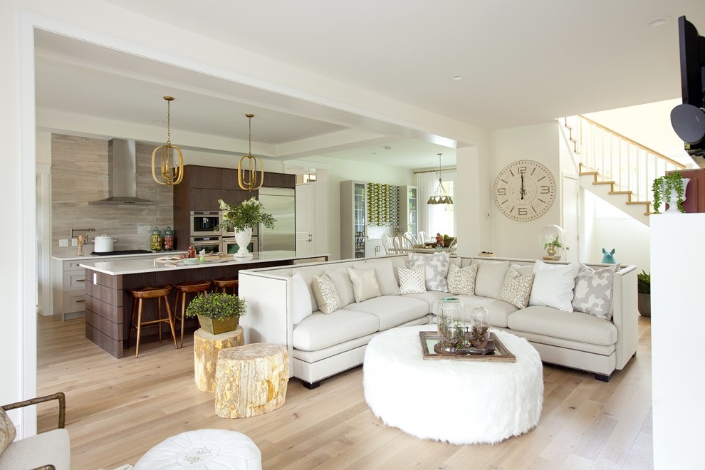 Transitional open concept living room in Vancouver with white walls, light hardwood floors and a wall-mounted tv.
