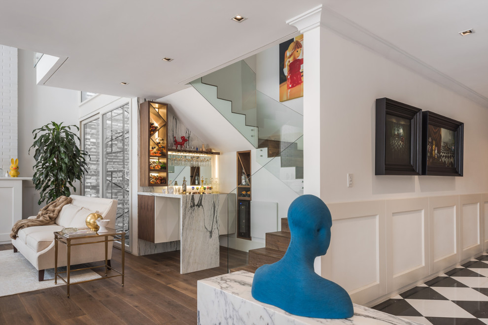 Contemporary l-shaped home bar in Miami with flat-panel cabinets, white cabinets, mirror splashback, medium hardwood floors, brown floor and white benchtop.