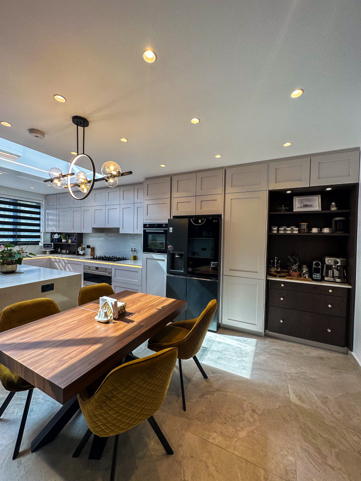 Photo of a large classic l-shaped kitchen/diner in London with a built-in sink, shaker cabinets, blue cabinets, quartz worktops, white splashback, engineered quartz splashback, integrated appliances, porcelain flooring, an island, beige floors, white worktops and feature lighting.