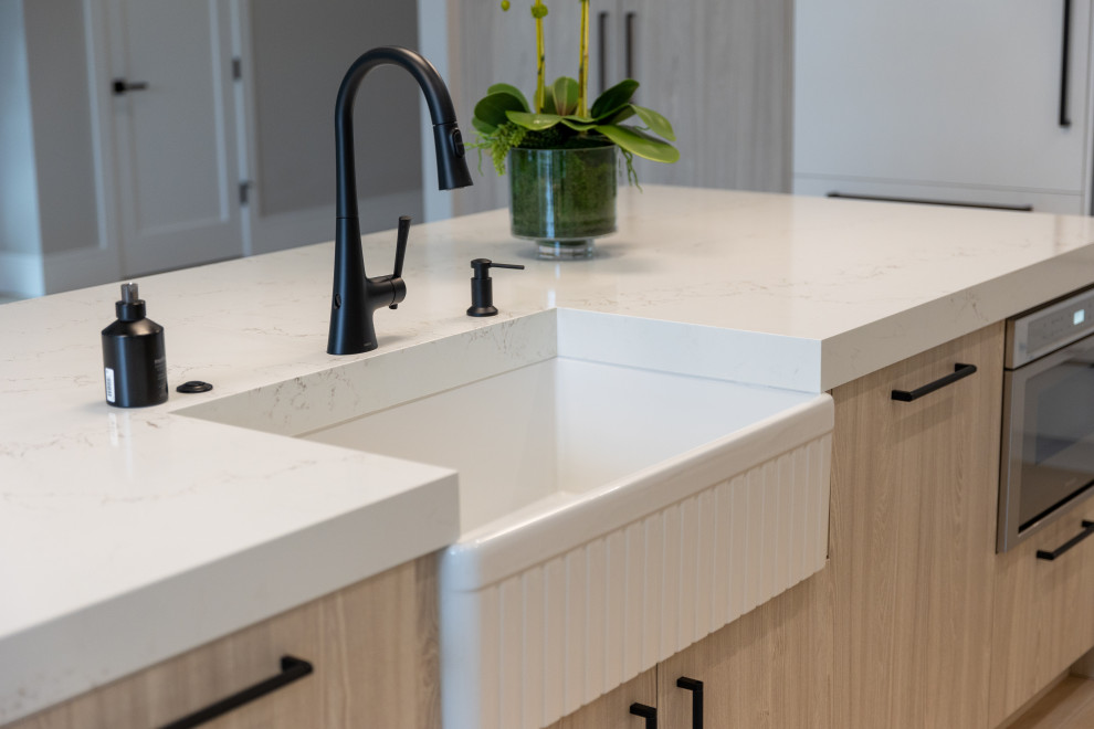 Example of a large transitional porcelain tile, brown floor and coffered ceiling kitchen design in Miami with a farmhouse sink, flat-panel cabinets, light wood cabinets, quartz countertops, an island and white countertops