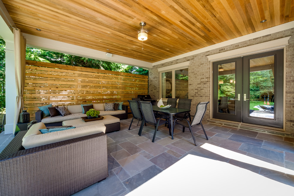 Design ideas for a large contemporary backyard patio in Toronto with natural stone pavers and a roof extension.