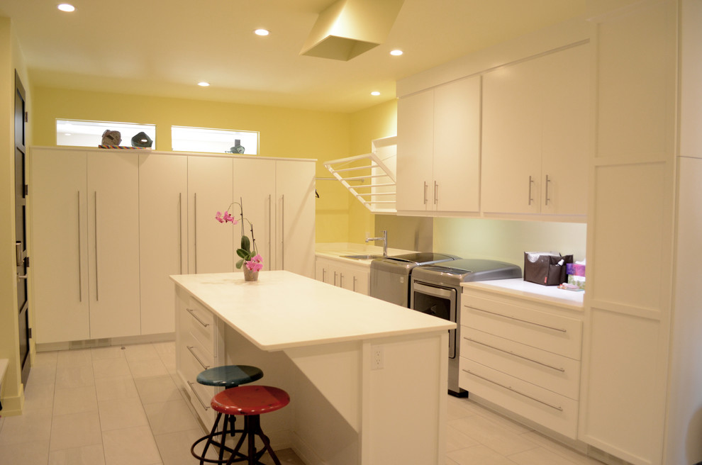 Photo of an expansive contemporary galley utility room in Other with a drop-in sink, flat-panel cabinets, white cabinets, quartz benchtops, yellow walls, porcelain floors and a side-by-side washer and dryer.