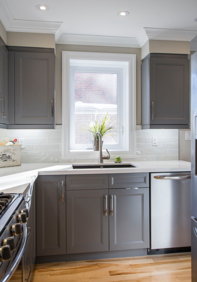 Kitchen - transitional brown floor kitchen idea with gray cabinets, quartz countertops, gray backsplash, ceramic backsplash, stainless steel appliances and white countertops