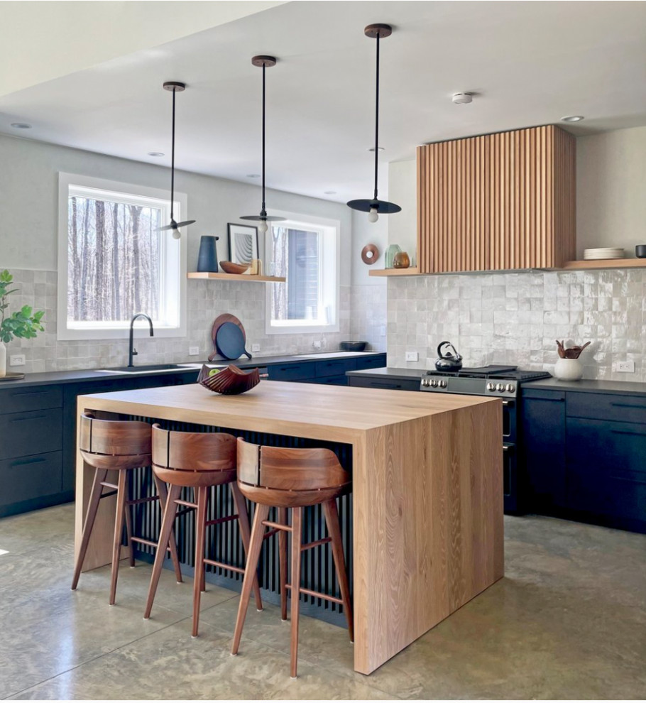 This is an example of a large midcentury open plan kitchen in New York with an undermount sink, flat-panel cabinets, medium wood cabinets, quartz benchtops, beige splashback, ceramic splashback, black appliances, concrete floors, with island, grey floor and grey benchtop.