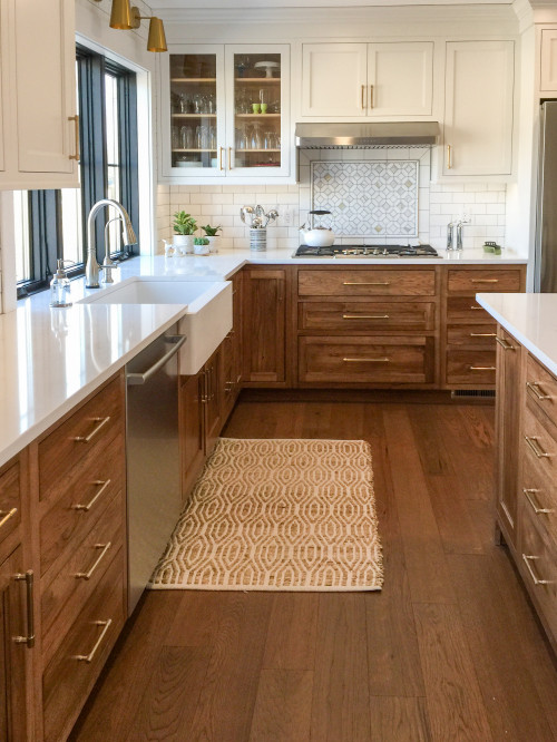 Warm transitional kitchen with white shaker uppers and natural wood RTA base cabinets, brass pulls, farmhouse sink, white quartz counters, and a patterned tile backsplash.
