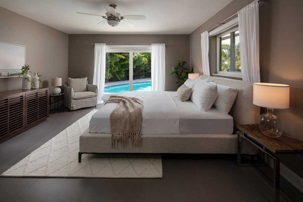 Design ideas for a large beach style master bedroom in Miami with brown walls, porcelain floors, no fireplace and grey floor.