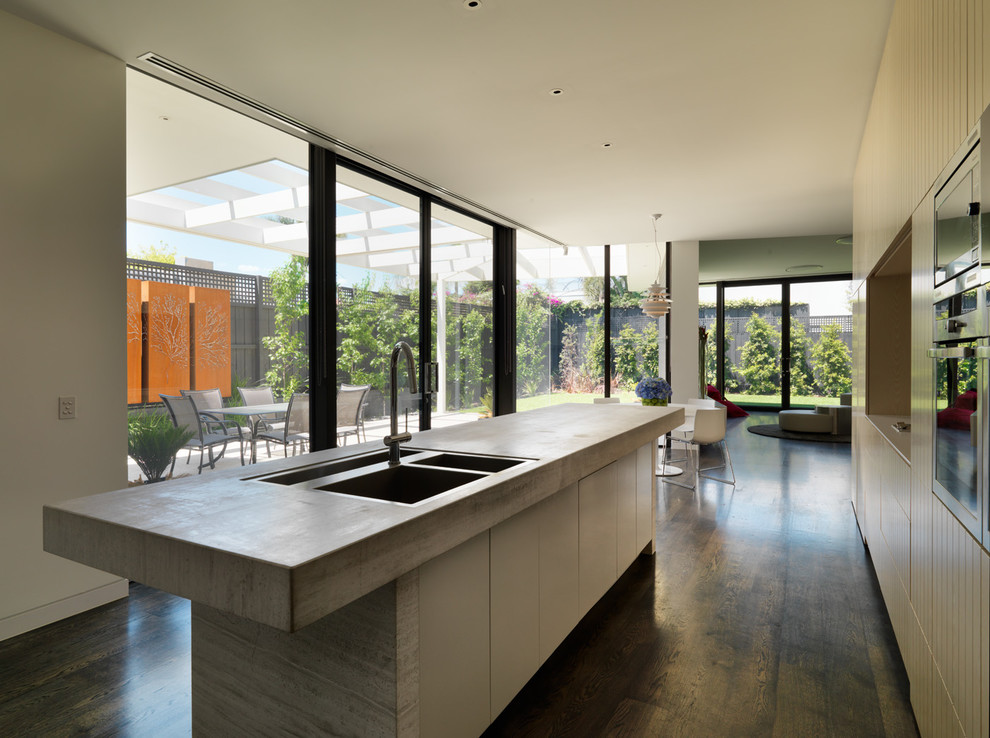 Design ideas for a mid-sized contemporary galley eat-in kitchen in Melbourne with a double-bowl sink, beige cabinets, marble benchtops, beige splashback, stone slab splashback, stainless steel appliances, dark hardwood floors and with island.
