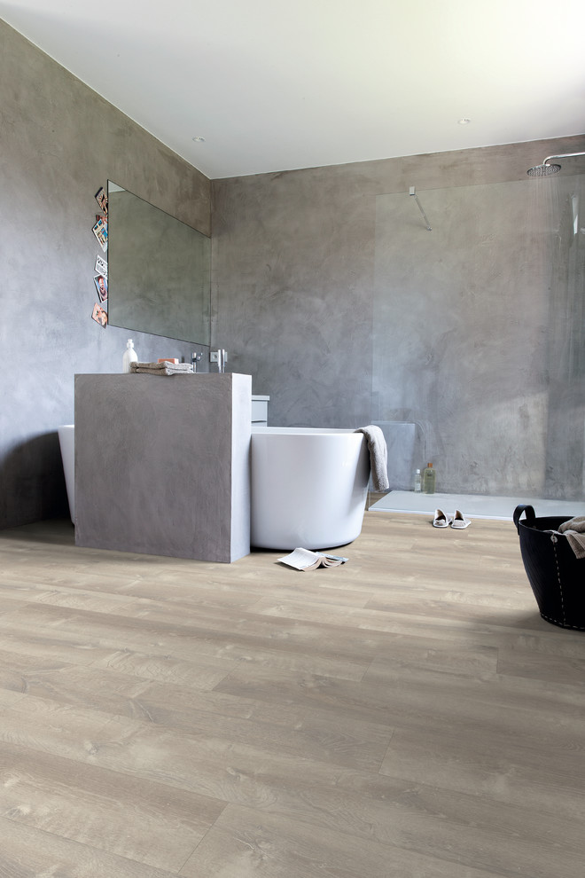 Photo of a large modern master bathroom with beige floor, a freestanding tub, grey walls and vinyl floors.
