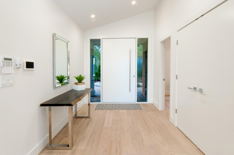 Photo of a transitional foyer in Vancouver with white walls, a pivot front door and a white front door.