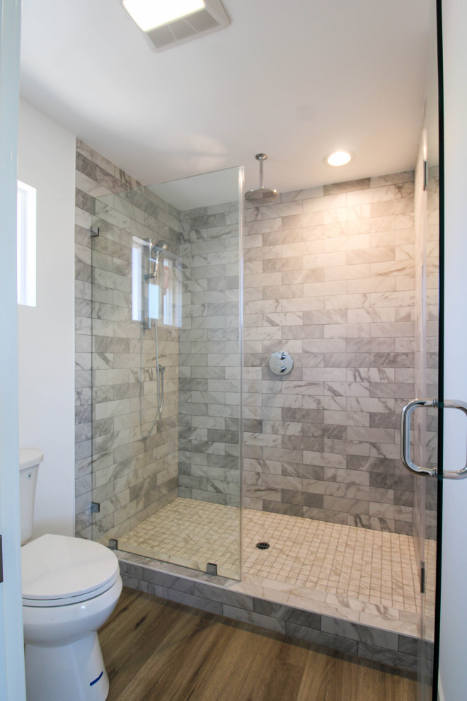 Mid-sized transitional 3/4 brown tile and ceramic tile laminate floor, brown floor and single-sink alcove shower photo in Los Angeles with shaker cabinets, brown cabinets, a two-piece toilet, beige walls, a drop-in sink, quartz countertops, a hinged shower door, beige countertops, a niche and a built-in vanity