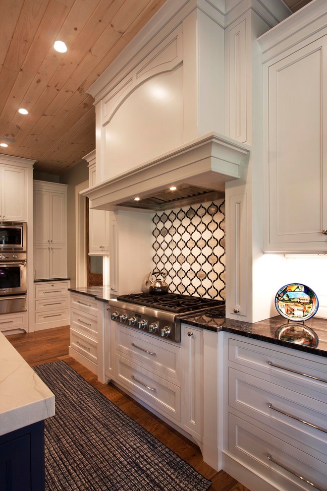 Eat-in kitchen - mid-sized transitional l-shaped light wood floor and brown floor eat-in kitchen idea with shaker cabinets, white cabinets, stainless steel appliances and an island