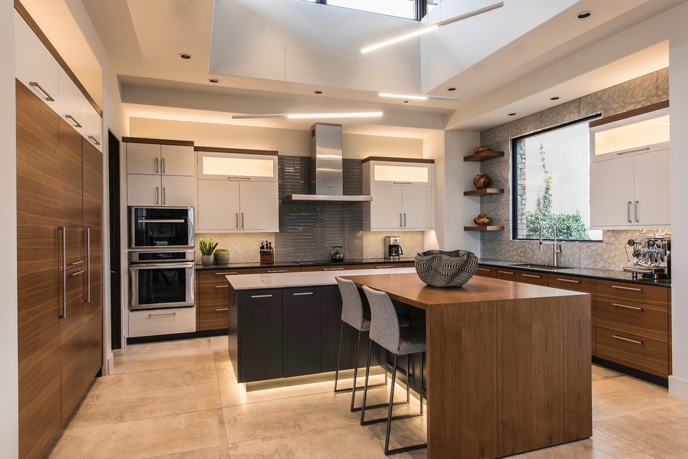 Design ideas for a large contemporary u-shaped eat-in kitchen in Phoenix with flat-panel cabinets, glass tile splashback, panelled appliances, multiple islands, an undermount sink, dark wood cabinets, solid surface benchtops, grey splashback, cement tiles, grey floor and black benchtop.