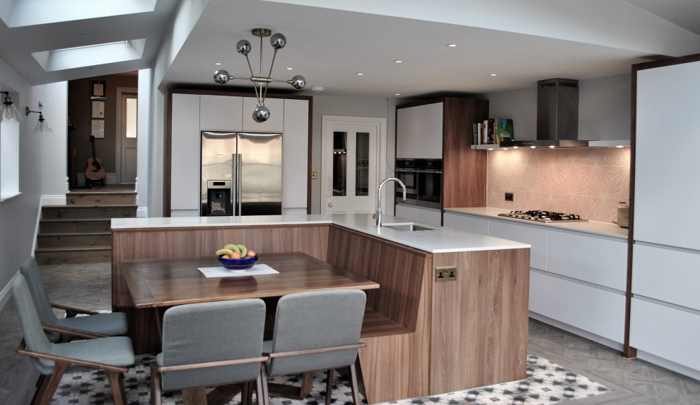 Photo of a large modern l-shaped eat-in kitchen in London with an integrated sink, flat-panel cabinets, white cabinets, solid surface benchtops, pink splashback, ceramic splashback, stainless steel appliances, linoleum floors, grey floor and grey benchtop.