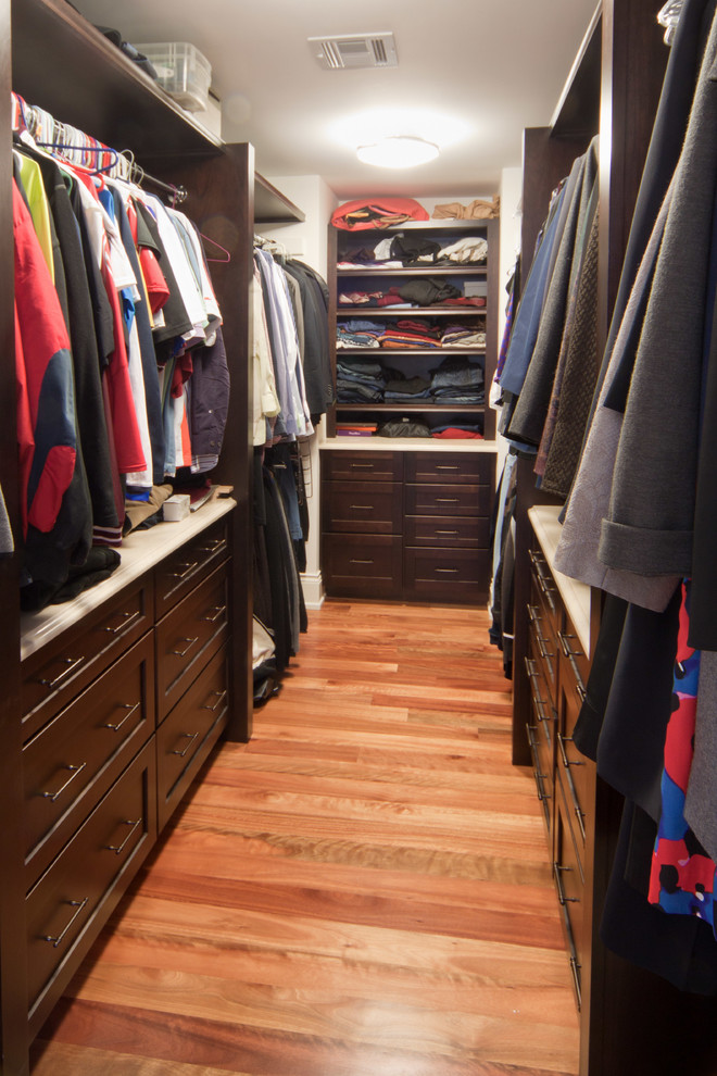 Photo of a large traditional gender-neutral walk-in wardrobe in Boston with shaker cabinets, dark wood cabinets and light hardwood floors.