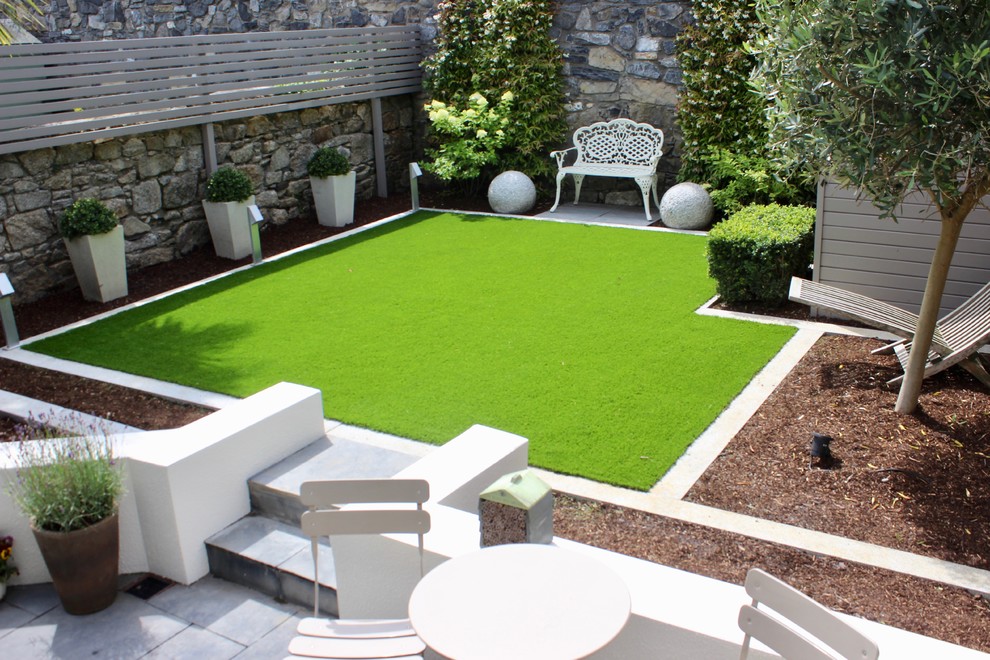 Small traditional backyard full sun formal garden in Dublin with with lawn edging, natural stone pavers and a stone fence for summer.