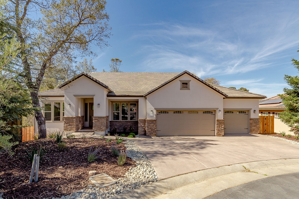Photo of a mid-sized country one-storey stucco beige house exterior in Sacramento with a gable roof and a shingle roof.