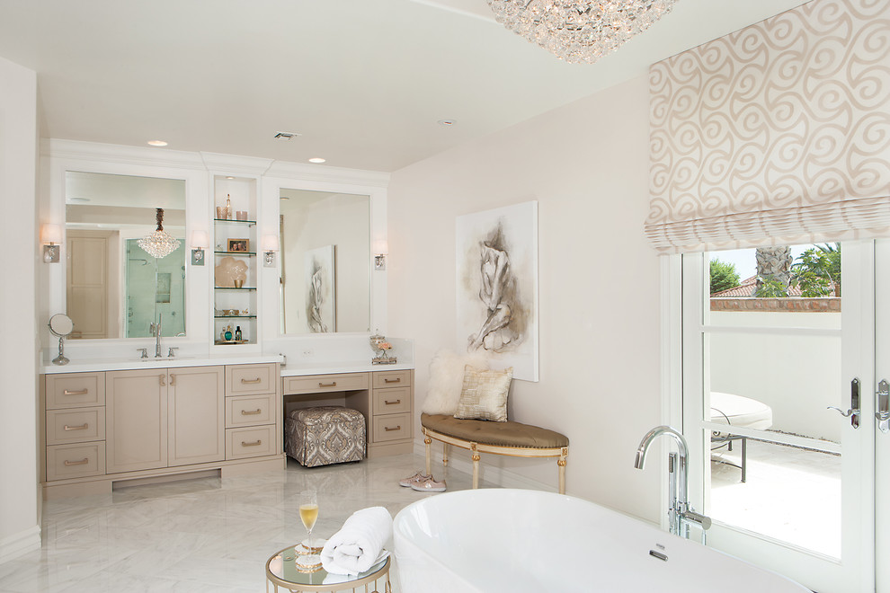 Example of a mid-sized transitional master white tile marble floor freestanding bathtub design in Phoenix with beige cabinets, beige walls and an undermount sink