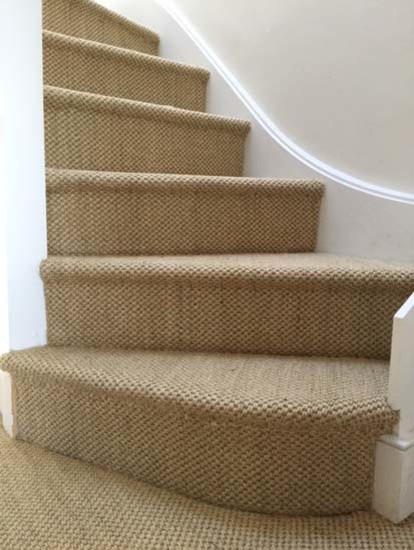 This is an example of a country carpeted u-shaped staircase in London with carpet risers and wood railing.