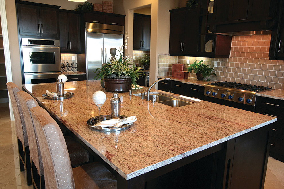 Eat-in kitchen - large transitional single-wall porcelain tile and beige floor eat-in kitchen idea in New York with a double-bowl sink, shaker cabinets, dark wood cabinets, granite countertops, beige backsplash, glass tile backsplash, stainless steel appliances and an island