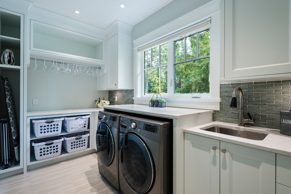 Inspiration for a large traditional single-wall utility room in Vancouver with an undermount sink, recessed-panel cabinets, white cabinets, quartz benchtops, white walls, porcelain floors, a side-by-side washer and dryer and grey floor.