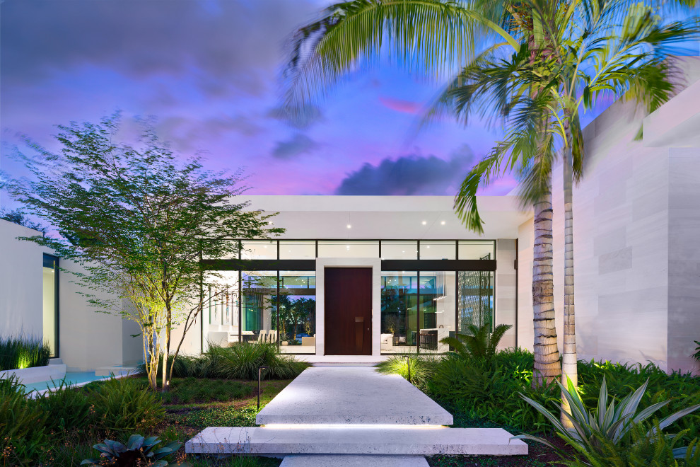 Photo of an expansive midcentury front door in Miami with multi-coloured walls, limestone floors, a pivot front door, a dark wood front door and beige floor.