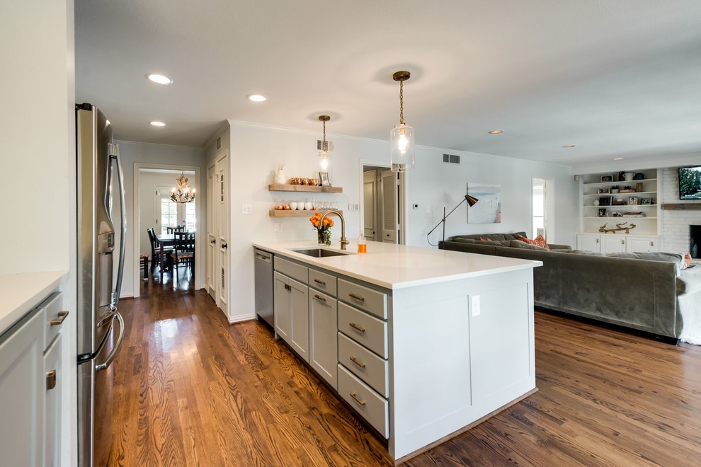 Photo of a mid-sized transitional single-wall open plan kitchen in Dallas with an undermount sink, shaker cabinets, grey cabinets, quartz benchtops, white splashback, mosaic tile splashback, stainless steel appliances, medium hardwood floors, with island and brown floor.