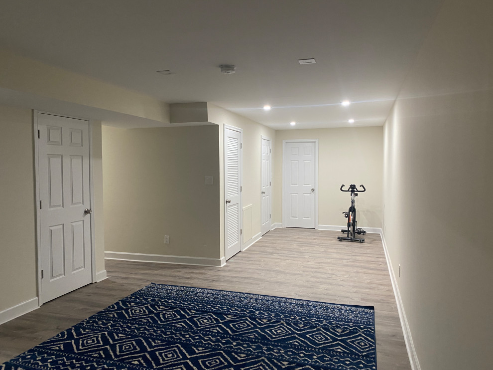 Aménagement d'un grand sous-sol moderne avec un bar de salon, un mur beige, un sol en vinyl et un sol marron.
