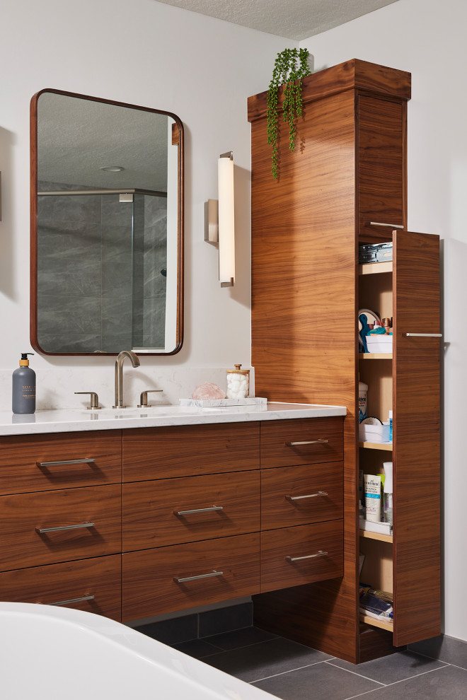 Photo of a large modern bathroom in Minneapolis with flat-panel cabinets, medium wood cabinets, a freestanding tub, a corner shower, gray tile, porcelain tile, white walls, porcelain floors, an undermount sink, engineered quartz benchtops, grey floor, a hinged shower door, white benchtops, a single vanity and a floating vanity.