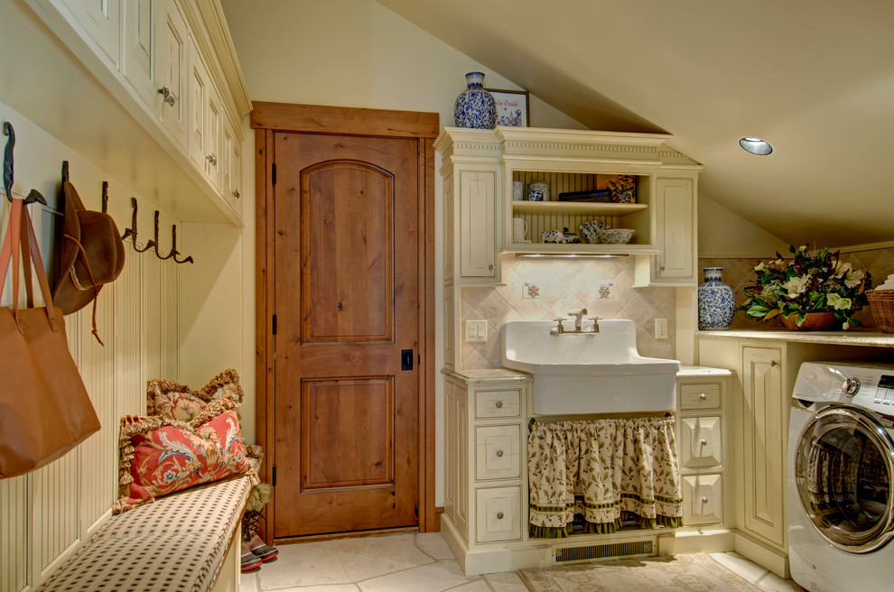 This is an example of a country laundry room in Denver with a farmhouse sink, beige cabinets, beige walls, a side-by-side washer and dryer, beige floor and beaded inset cabinets.
