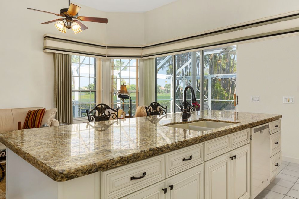 Mid-sized traditional l-shaped eat-in kitchen in Miami with raised-panel cabinets, beige cabinets, granite benchtops, with island, yellow benchtop, a drop-in sink, yellow splashback, granite splashback, white appliances and ceramic floors.