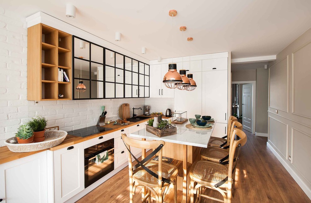 Kitchen - transitional l-shaped medium tone wood floor kitchen idea with shaker cabinets, white cabinets, wood countertops, white backsplash, brick backsplash and an island