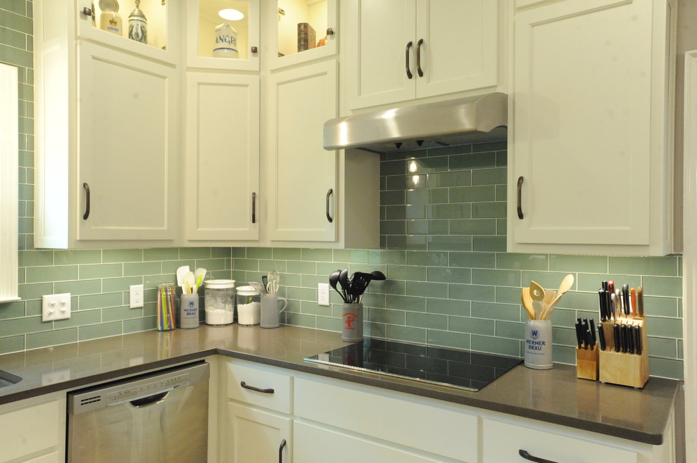 Inspiration for a transitional u-shaped travertine floor kitchen remodel in Atlanta with a single-bowl sink, recessed-panel cabinets, white cabinets, quartz countertops, green backsplash, glass tile backsplash, stainless steel appliances and an island