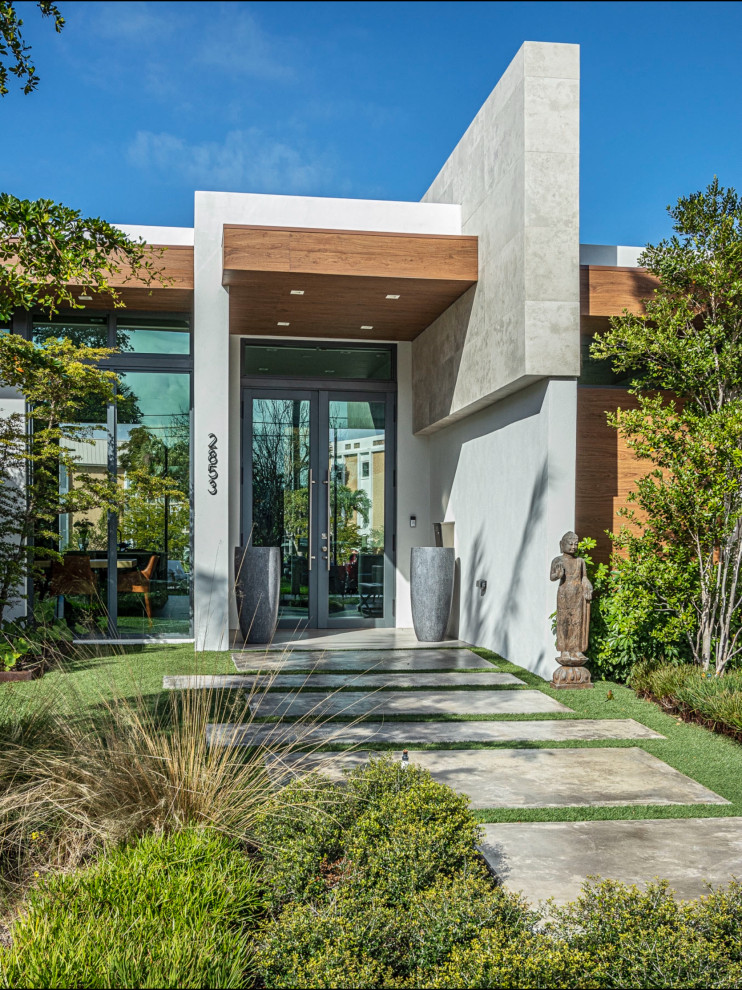 This is an example of a contemporary entryway in Miami with a single front door and a glass front door.