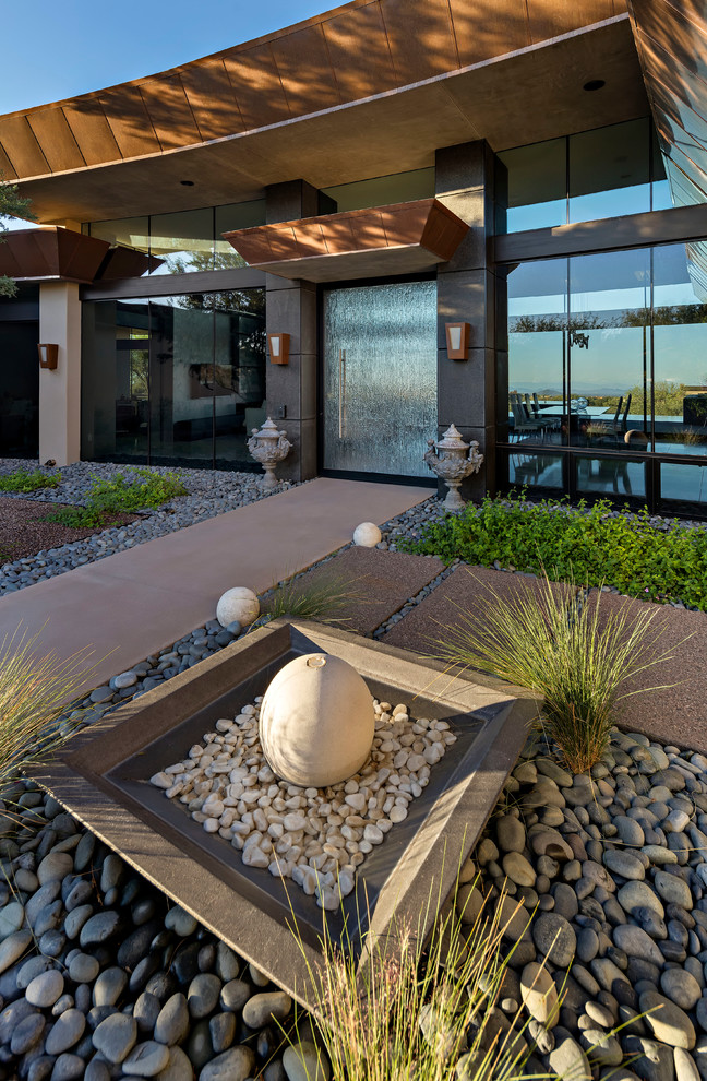 This is an example of a large modern one-storey adobe beige exterior in Phoenix with a flat roof.